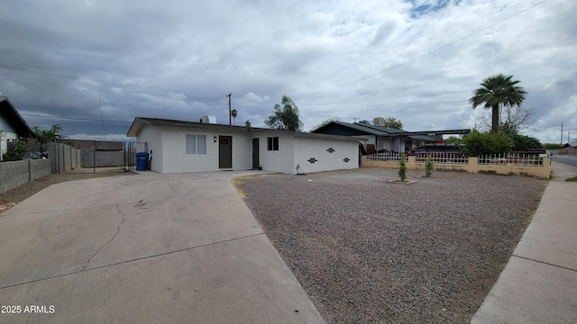 ranch-style house with driveway, fence, stucco siding, and a gate