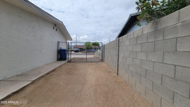 view of side of property featuring a gate, stucco siding, and fence