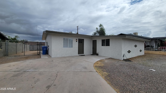 single story home featuring stucco siding, a gate, and fence