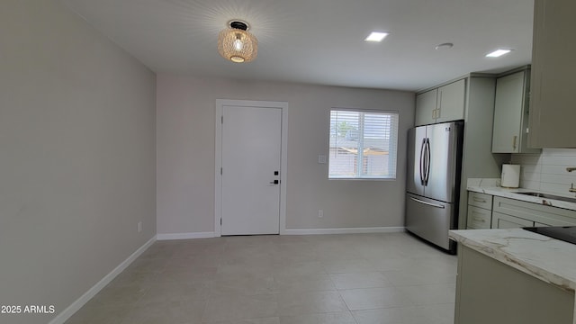 kitchen with freestanding refrigerator, a sink, baseboards, gray cabinets, and light tile patterned floors