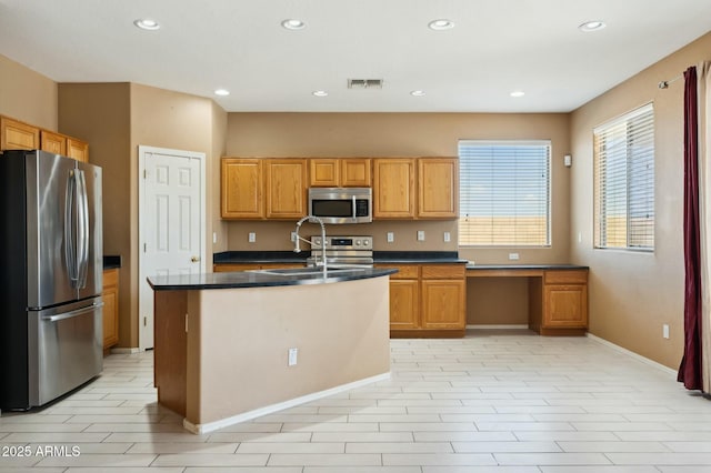 kitchen with a sink, appliances with stainless steel finishes, dark countertops, visible vents, and recessed lighting
