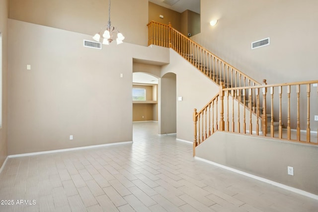interior space featuring stairs, a notable chandelier, wood finished floors, visible vents, and arched walkways