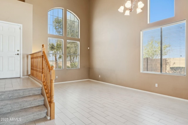 staircase featuring a towering ceiling, a notable chandelier, and baseboards