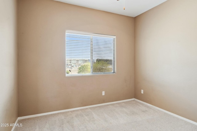 spare room with baseboards, ceiling fan, and carpet