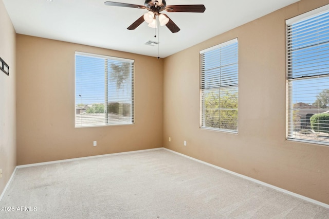 carpeted spare room with baseboards, visible vents, and a ceiling fan