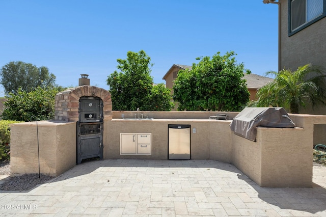 view of patio / terrace with an outdoor kitchen, area for grilling, a gate, and a sink