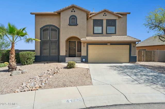 view of front of home with driveway, stucco siding, a tile roof, and fence