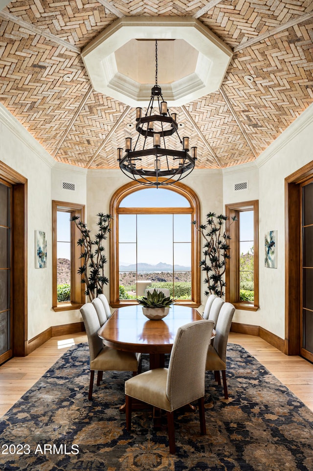 dining room featuring a wealth of natural light, crown molding, a notable chandelier, and light wood-type flooring