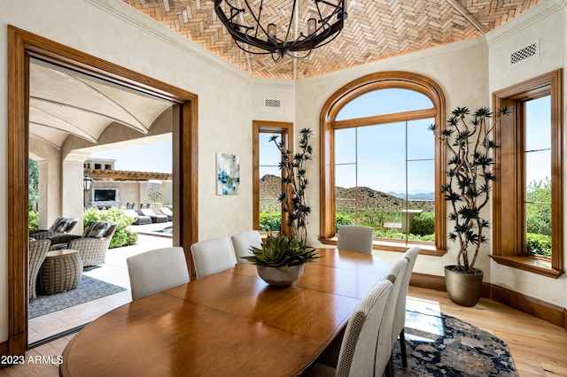 dining space with brick ceiling, a notable chandelier, light hardwood / wood-style floors, crown molding, and a mountain view