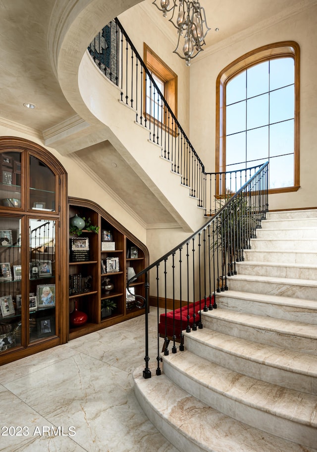 stairway featuring ornamental molding, a notable chandelier, and a healthy amount of sunlight