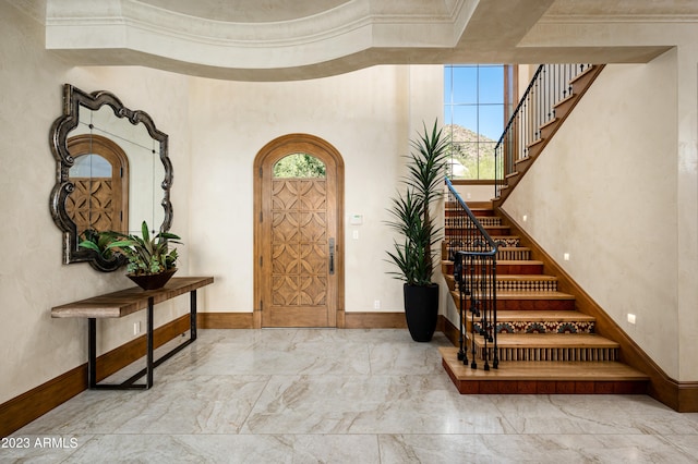 entryway with ornamental molding and a high ceiling