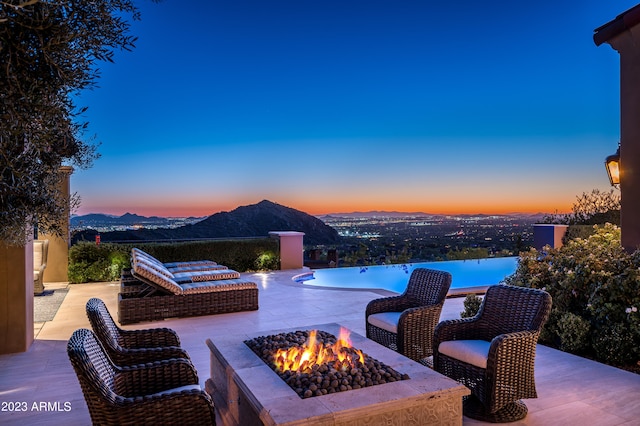 patio terrace at dusk with an outdoor fire pit and a mountain view