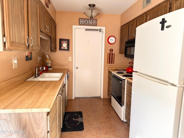 kitchen featuring sink, light tile patterned floors, and white appliances