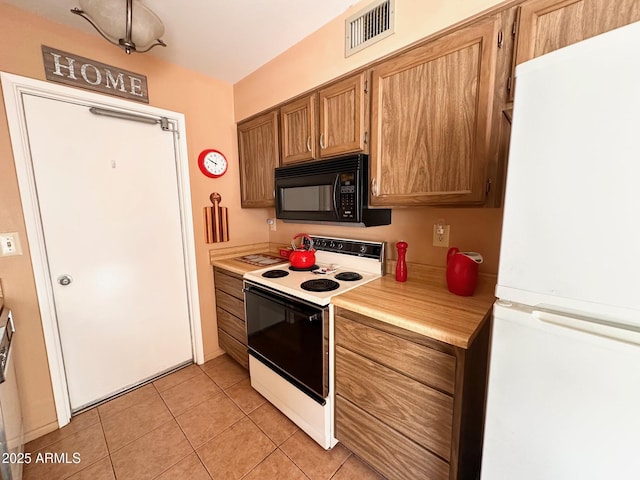 kitchen with light tile patterned floors, range with electric cooktop, and white refrigerator