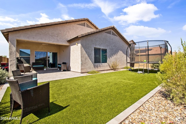 back of house featuring a trampoline, an outdoor hangout area, a lawn, and a patio