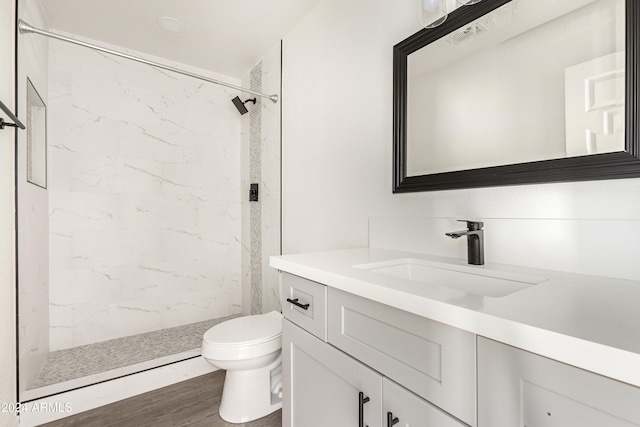 bathroom featuring tiled shower, wood-type flooring, vanity, and toilet