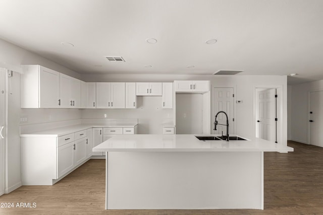 kitchen featuring light hardwood / wood-style flooring, a center island with sink, white cabinetry, and sink