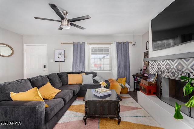 living room featuring ceiling fan and a tiled fireplace