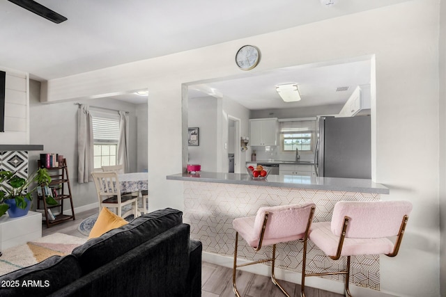 kitchen with sink, stainless steel appliances, light hardwood / wood-style floors, white cabinets, and kitchen peninsula