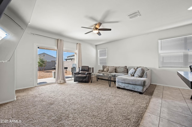 living area featuring light tile patterned floors, visible vents, a ceiling fan, and baseboards