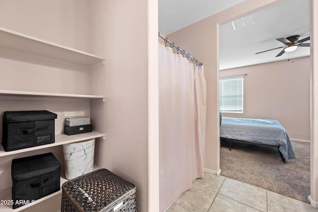 ensuite bathroom with connected bathroom, curtained shower, a ceiling fan, and tile patterned flooring