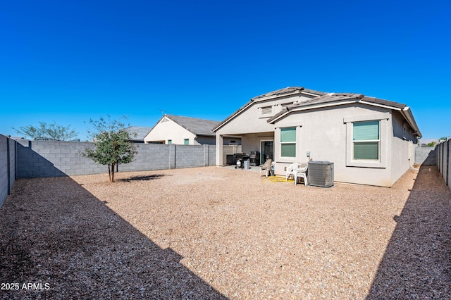 rear view of house with stucco siding, central air condition unit, and a fenced backyard