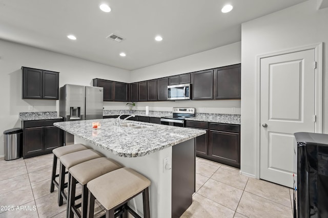 kitchen with a breakfast bar area, a center island with sink, visible vents, a sink, and stainless steel appliances