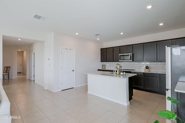 kitchen featuring recessed lighting, visible vents, appliances with stainless steel finishes, decorative backsplash, and light stone countertops