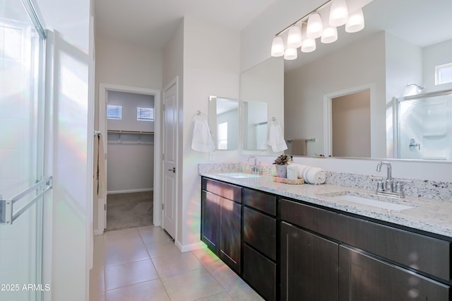 full bathroom featuring a spacious closet, a stall shower, tile patterned flooring, and a sink