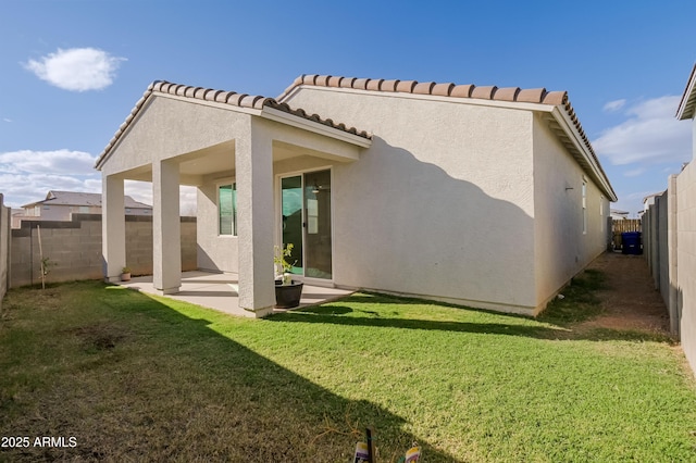 rear view of house with a tile roof, stucco siding, a lawn, a patio area, and a fenced backyard