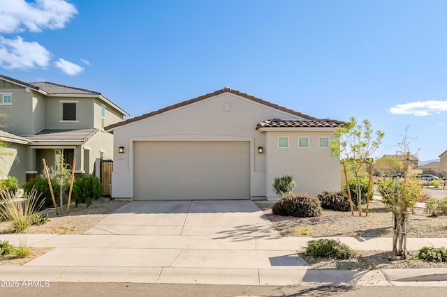 view of front facade featuring concrete driveway, an attached garage, a tile roof, and stucco siding