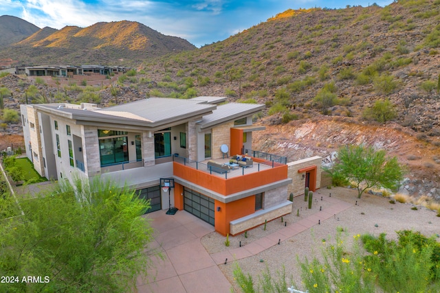 rear view of property with a balcony, a garage, and a mountain view