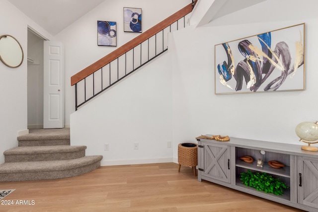 stairway with wood-type flooring and vaulted ceiling