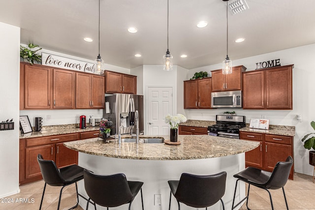 kitchen featuring a center island with sink, a breakfast bar area, appliances with stainless steel finishes, sink, and decorative light fixtures