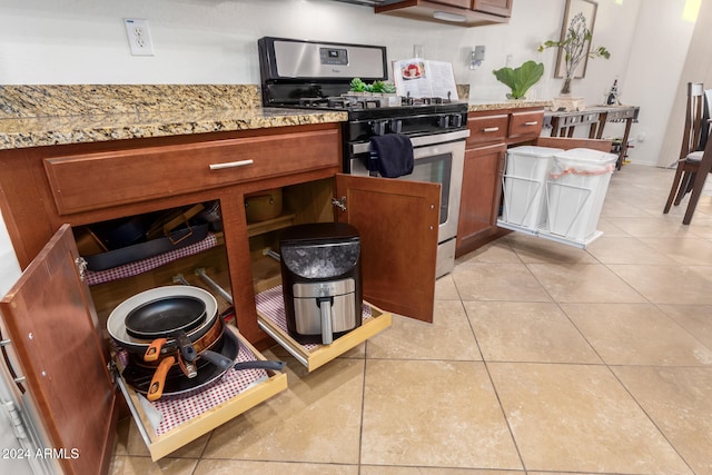 kitchen featuring light stone countertops, gas stove, and light tile patterned floors