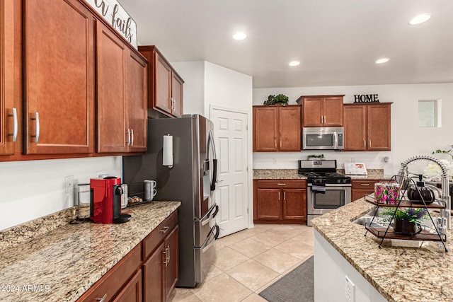 kitchen with light stone countertops, sink, appliances with stainless steel finishes, and light tile patterned flooring