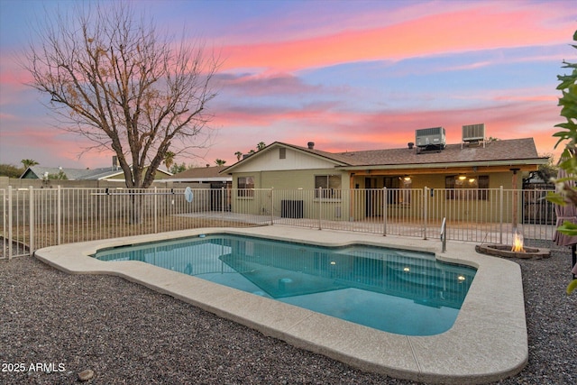 pool at dusk featuring central AC unit and a patio area