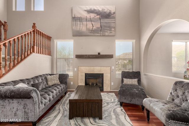 living area featuring a fireplace, stairs, a towering ceiling, and wood finished floors