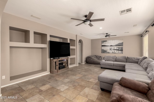 living room with ceiling fan, visible vents, arched walkways, and built in shelves