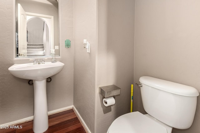 bathroom featuring toilet, wood finished floors, and baseboards