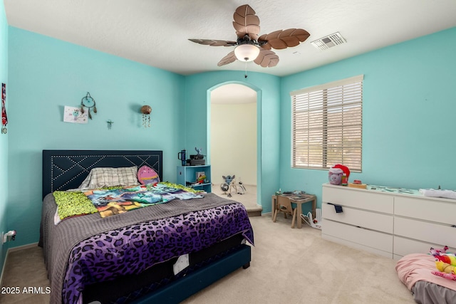 bedroom featuring a ceiling fan, visible vents, baseboards, arched walkways, and carpet flooring