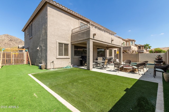 back of house featuring a patio, a balcony, a fenced backyard, stucco siding, and a playground