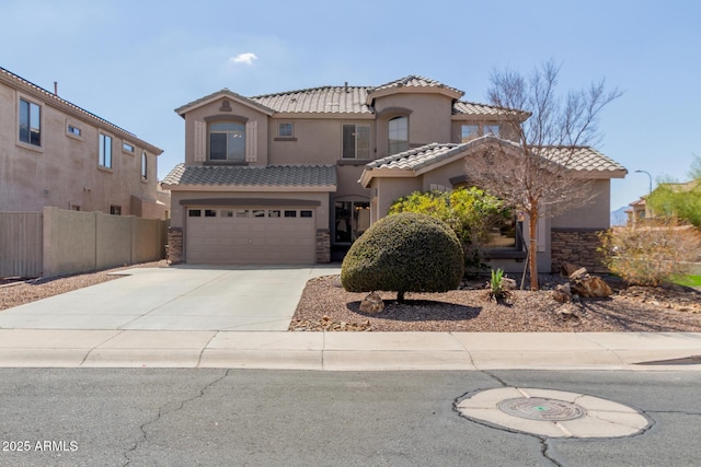 mediterranean / spanish home with a tile roof, stucco siding, concrete driveway, and a garage