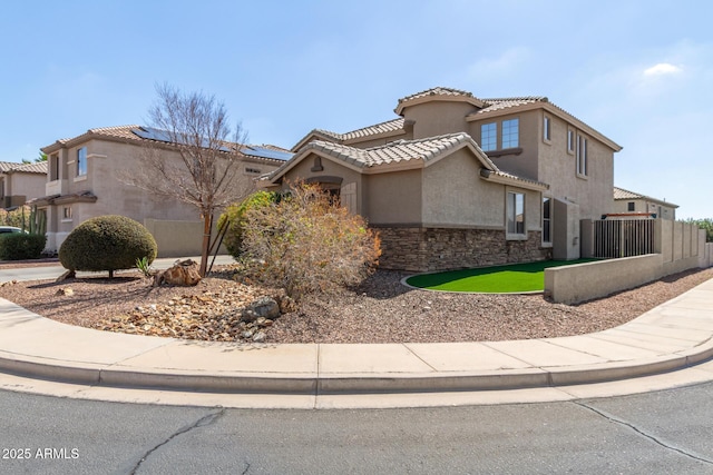 view of front of house with a tiled roof, stucco siding, stone siding, and fence