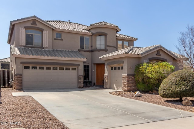 mediterranean / spanish house featuring concrete driveway, a tiled roof, stone siding, and stucco siding