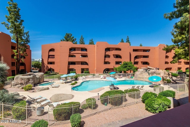 community pool with a patio area and fence