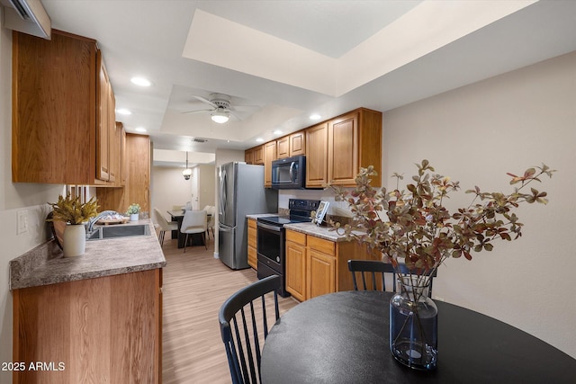 kitchen with black microwave, range with electric cooktop, a sink, freestanding refrigerator, and a tray ceiling