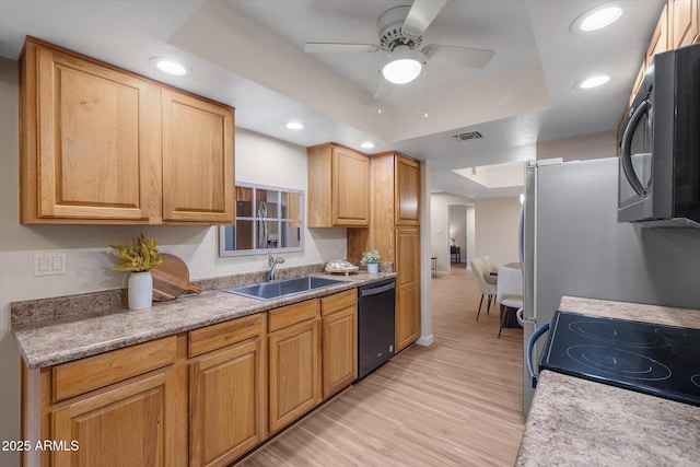 kitchen featuring a sink, visible vents, black appliances, light wood finished floors, and a raised ceiling