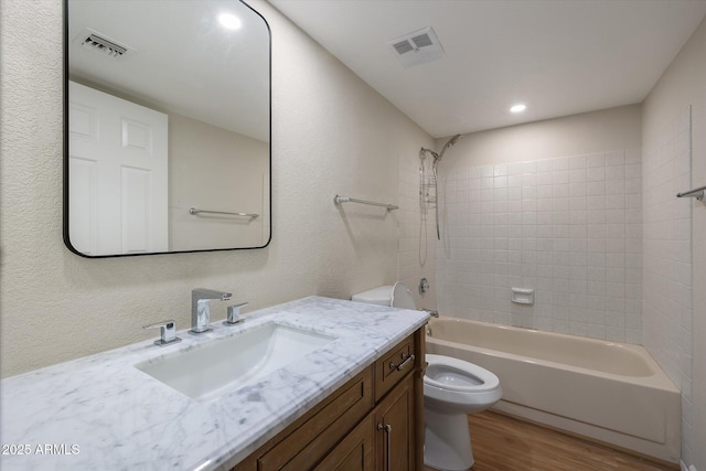 full bath with toilet, washtub / shower combination, visible vents, and wood finished floors