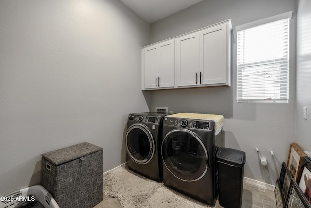 clothes washing area with cabinets, light hardwood / wood-style floors, and independent washer and dryer